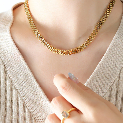 Gold multi-row woven mesh necklace worn on beige V-neck top
