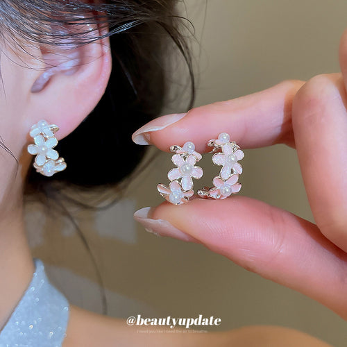 Styled wear view of 粉白花朵C形耳钉 showing small open hoops lined with pastel five-petal flowers and silver-tone edges