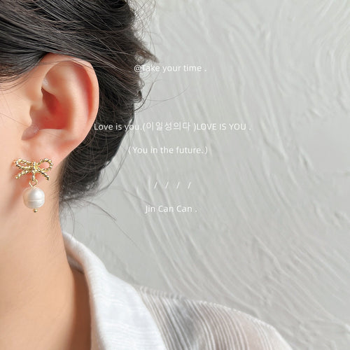 Gold twisted rope bow pearl drop stud worn on ear side view