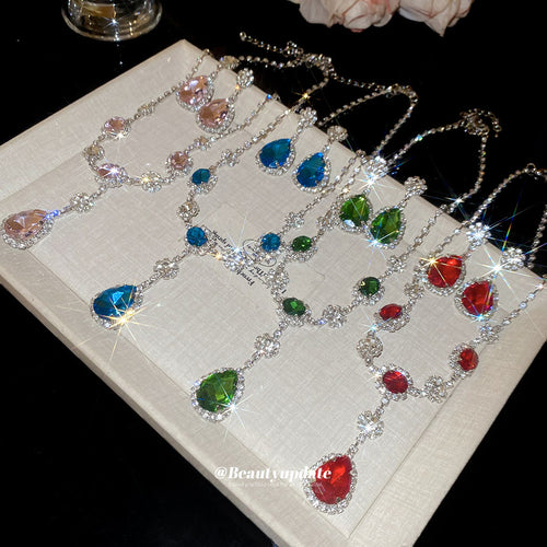 Pink blue green red rhinestone teardrop necklaces laid on cream tray