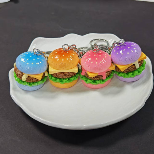 Row of four colorful resin burger keychains on white plate