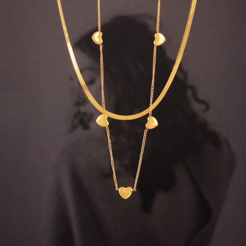 Hanging gold heart station and herringbone necklaces with portrait backdrop