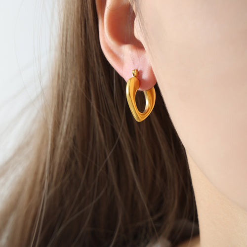 Gold heart teardrop hoop earring worn on model ear