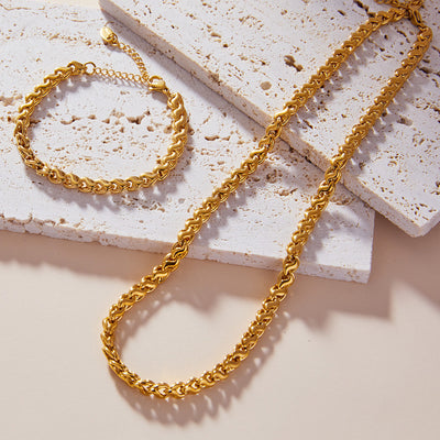 Gold twisted cuban link necklace and bracelet on stone tiles