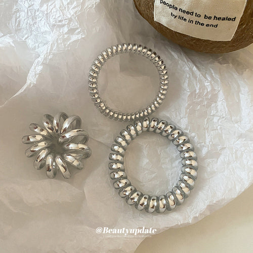 silver metallic spiral coil hair tie in the listed medium style shown worn in a styled second view