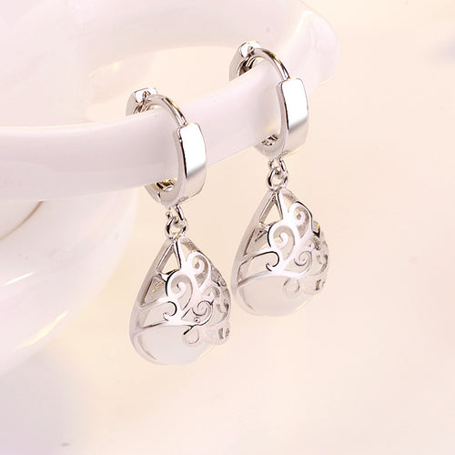 Silver white cat-eye teardrop drops hanging on white ceramic