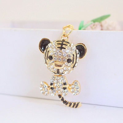 Front close-up of a gold-tone tiger charm covered with clear rhinestones and black details.