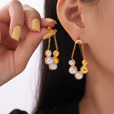 Gold pearl cluster chain drop earrings worn and held near ear