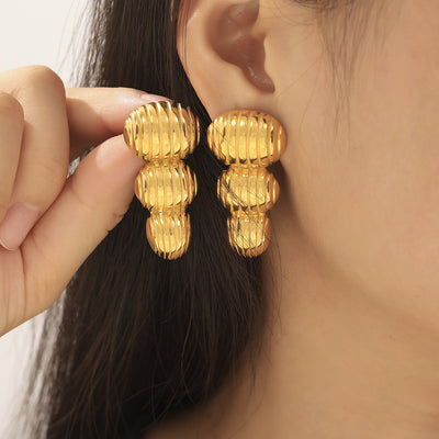 Model wearing gold ribbed three-segment peanut drop earrings close-up