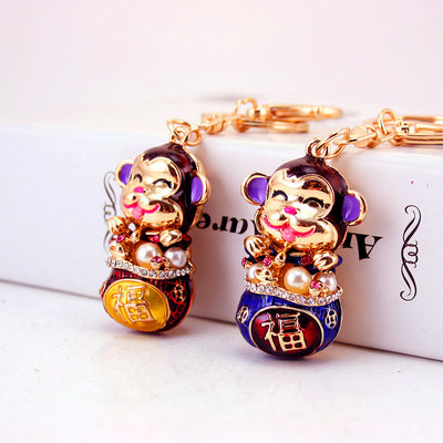 Two smiling monkey keychains in red and blue are shown side by side.