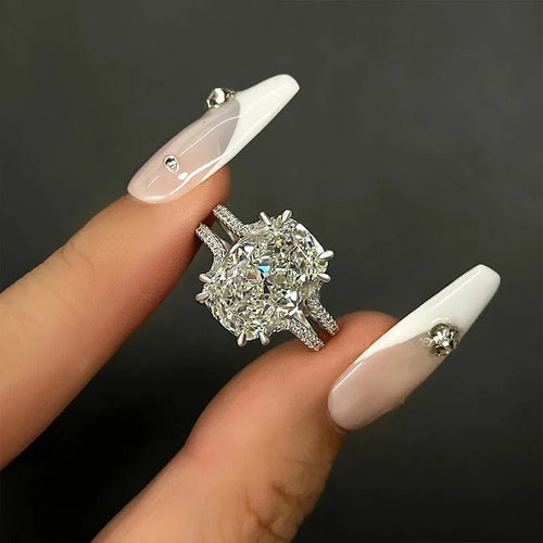Large silver rectangle clear double-band ring held between fingers dark background