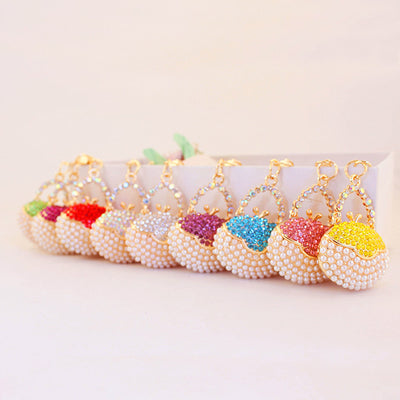 A row of handbag-shaped charms with white pearl-like bead bodies and assorted colored stone tops.