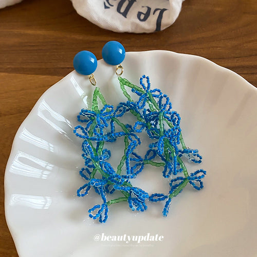 Blue seed-bead flower cascades beneath round blue studs in a close product view.