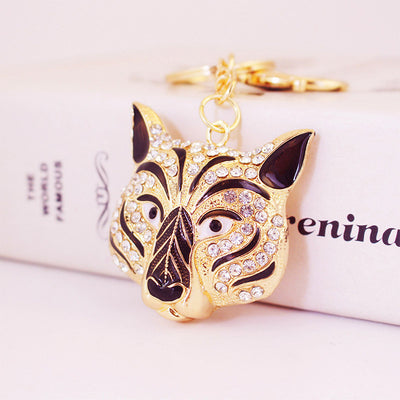 Close-up of a gold-tone tiger head keychain with clear rhinestones and black enamel details.