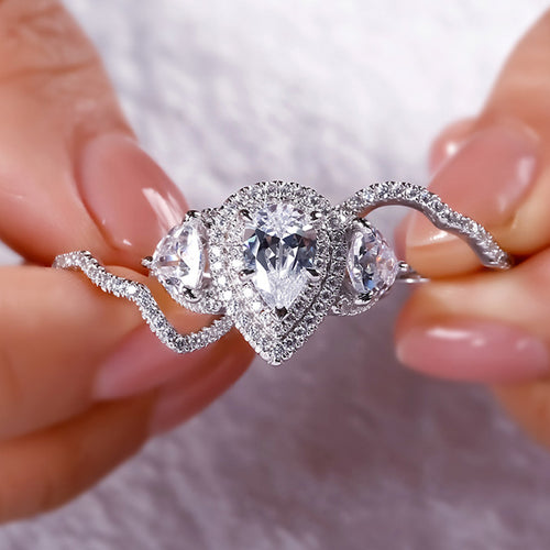 Pear halo main ring and two wavy guard bands held between fingers