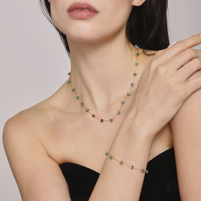 Model wearing gold teal stone bead necklace and matching bracelet