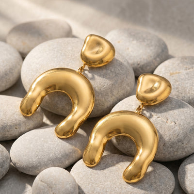 Pair of gold hammered U-shape drop earrings on pale stones