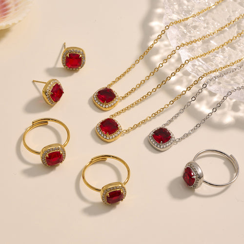 Flat lay of gold and steel red cushion necklace ring and stud set