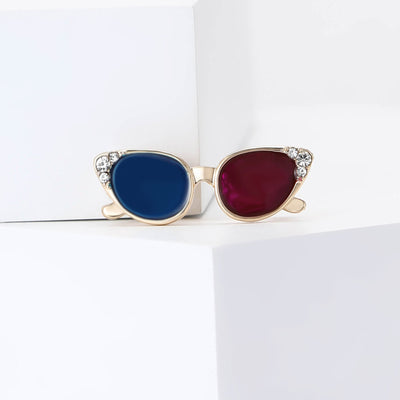 Blue and magenta enamel sunglasses brooch on white blocks