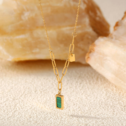 Close-up gold paperclip links and green striped pendant