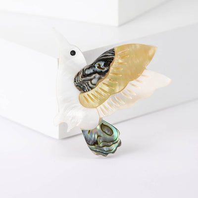 Front view of shell Effect Flying Bird Brooch With Iridescent Perch against a white background.