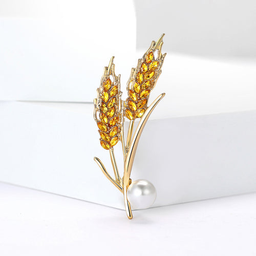 Angled display of the wheat stalk brooch on a white surface