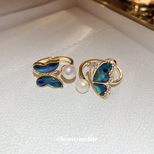 gold-tone open ring with an iridescent butterfly and pearl-like beads shown worn in a styled second view