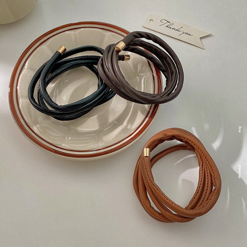 multi-loop leather-look ponytail wrap with gold-tone capped ends shown worn in a styled second view