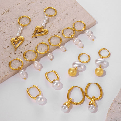 Mixed gold pearl hoop earring styles laid on marble surface
