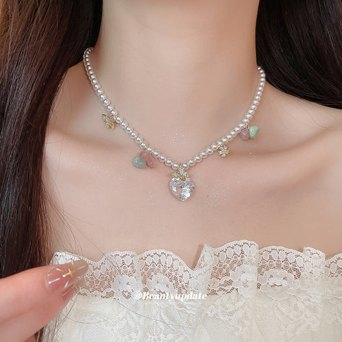 Primary view of a pearl-like strand with pastel stone chips, small gold tone butterflies, and a clear heart drop