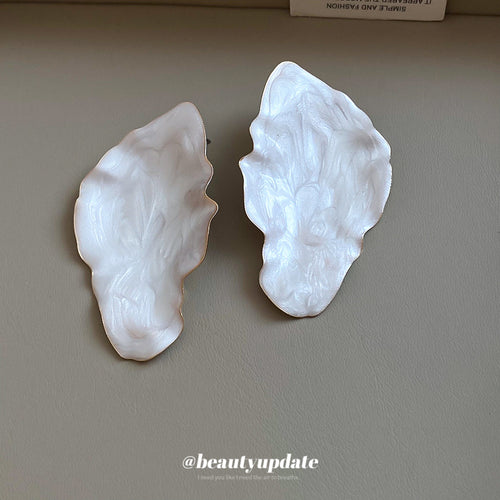 Large irregular leaf silhouettes with a rippled pearly white surface displayed in a close product arrangement.