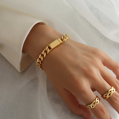Gold curb chain magnetic clasp bracelet worn on wrist with twisted gold rings