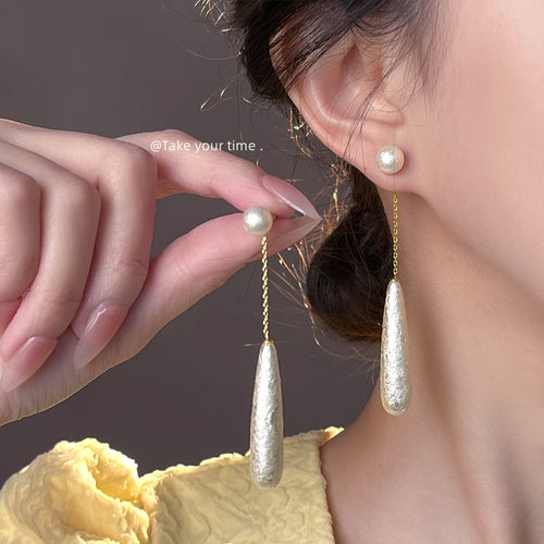 Gold-tone pearl-like long-teardrop chain studs in the first product display.