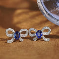 White Metal Bow Stud Earrings Blue Oval Center Pavé Stones view 1