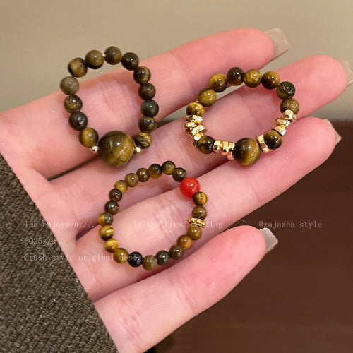 Three tiger eye bead ring styles held in open palm