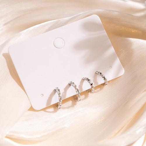 Four silver crystal mini huggie studs on white card on satin
