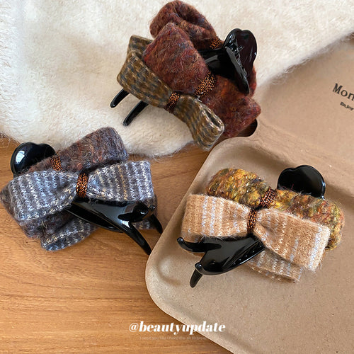 Three black-base dual wool bow claw clips on tray