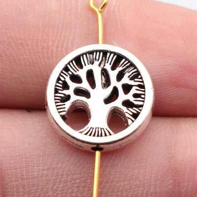 Antique Silver 生命树圆形穿孔珠 displayed on fingertips
