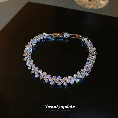 silver-tone tennis bracelet with repeating clear crystal flower links shown worn in a styled second view