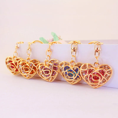 Six gold-tone heart keychains displayed in a row with different colored faceted stones.