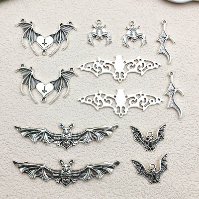Antique silver bat and cross charms arranged on a light background