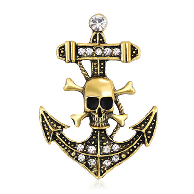 Front view of the skull and anchor brooch in antique gold or silver with polished metal detail on a white background