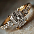 Emerald-Cut Clear Solitaire Ring With Round Side Stones In Gold Tone view 1