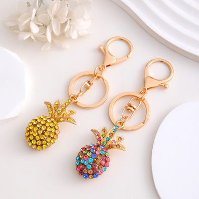Yellow and multicolor rhinestone pineapple keychains side by side