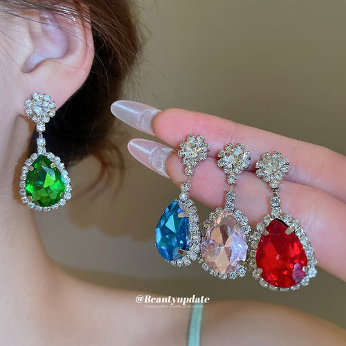 Green teardrop earring worn with blue pink red pairs held in hand