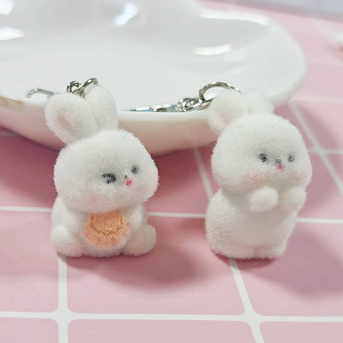 Pair of white flocked bunnies one with peach belly one praying pose