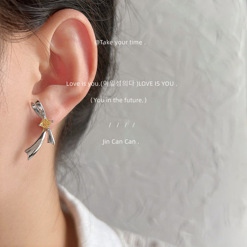 Silver yellow bow stud earring worn on ear