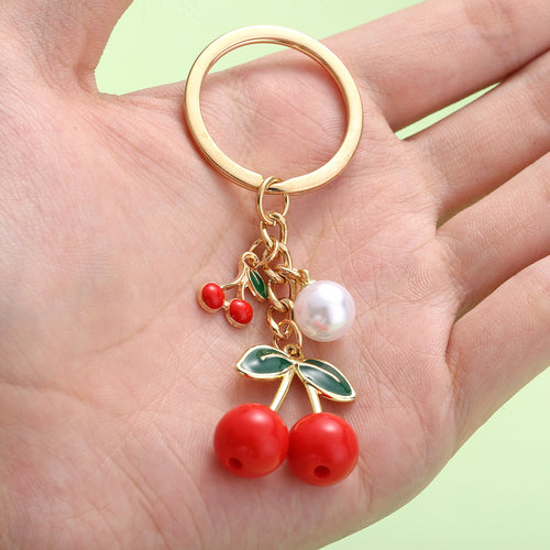 Image 2 showing a person holding a gold ring with cher and cherry charms.