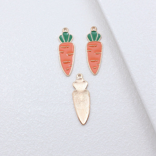 Long pink carrot enamel charm arranged on a natural wood surface
