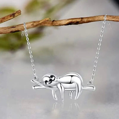 White metal sloth branch pendant necklace hanging on wood stick